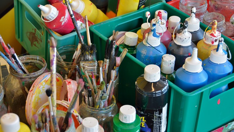 Maling og pensler i kasser på et bord
