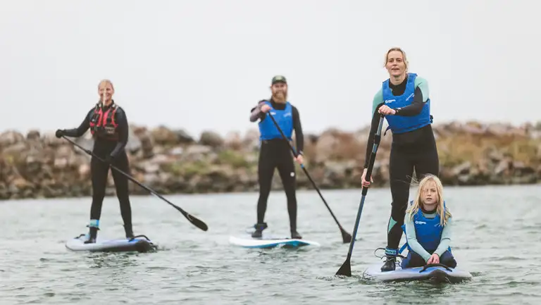 Børn og voksne på paddleboard i Klintholm Havn