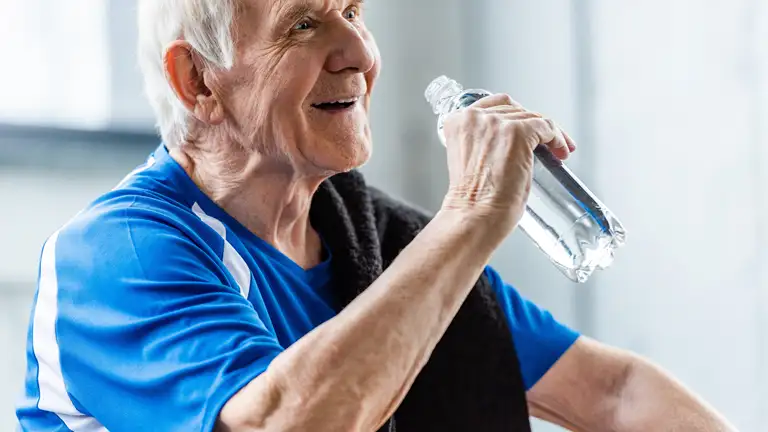 Ældre mand drikker vand under træning