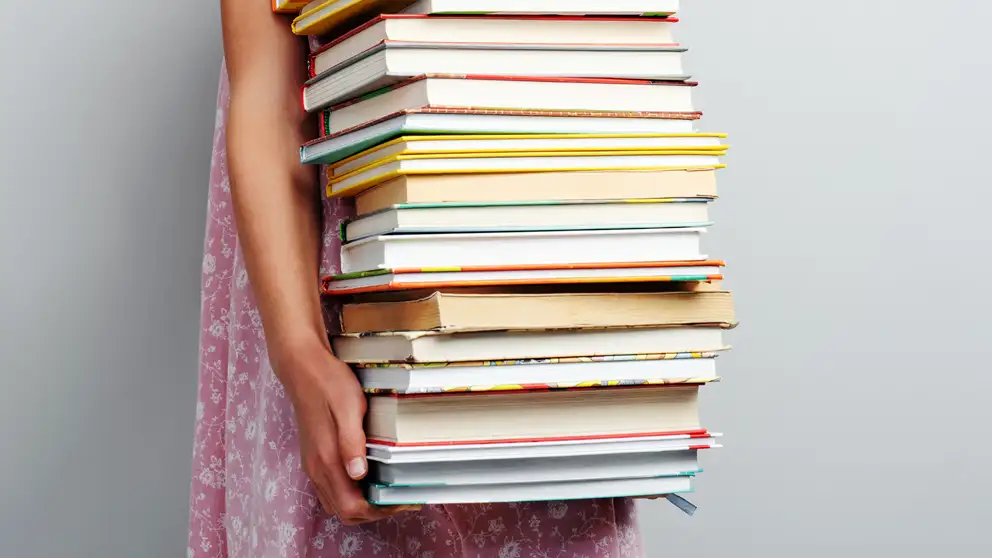 Pige, der holder en bunke bøger