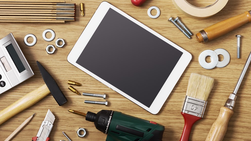 Billede af forskelligt værktøj og en tablet, der ligger på et bord