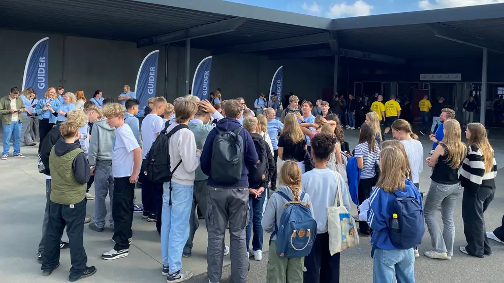 Unge mennesker samlet foran bygning