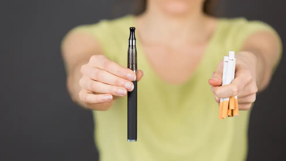 Kvinde der holder en vape og cigaretter