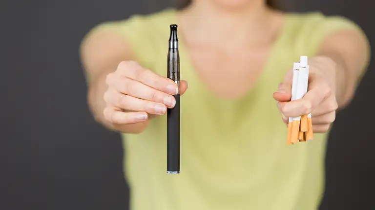 Kvinde der holder en vape og cigaretter