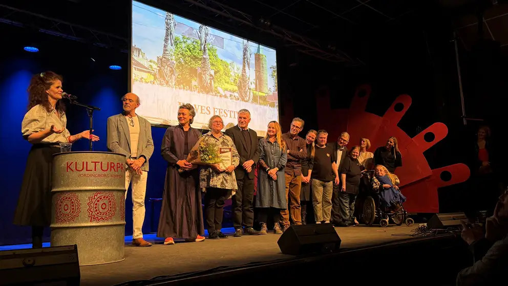 Billede af mennesker fra Waves Festival der får overrakt Publikumsprisen på en scene 