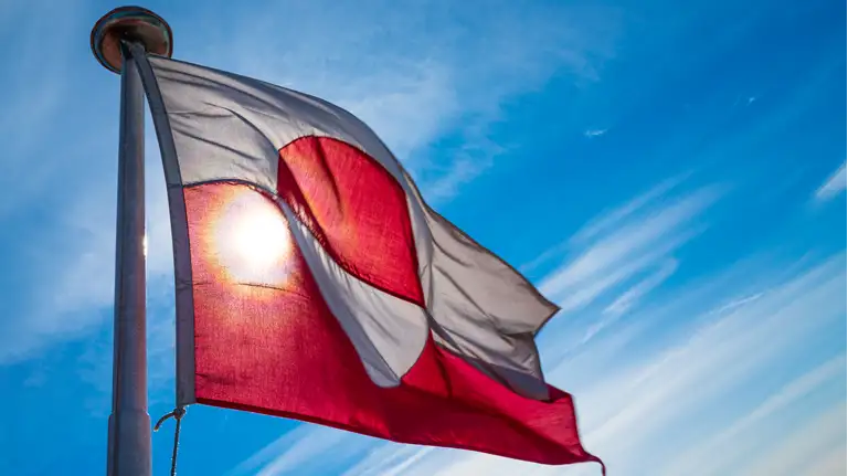 Billede af det grønlandske flag i en flagstand på en solskinsdag