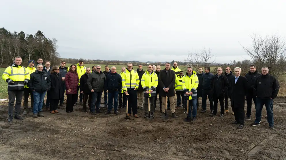 Billede af en forsamling mennesker. Fire står forrest med hver deres spade i hånden