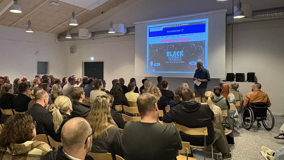 Billede af en forsamling mennesker, der lytter til et oplæg